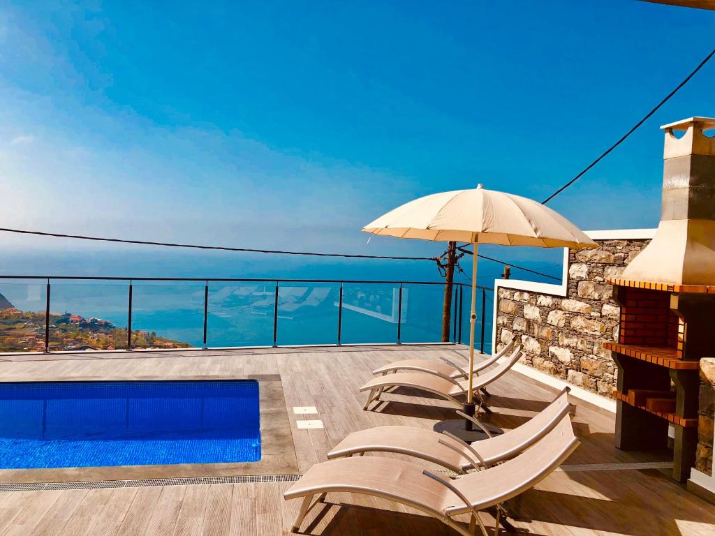 a patio with chairs and an umbrella and a swimming pool at Villa da Bisa with heated swiming pool in Arco da Calheta