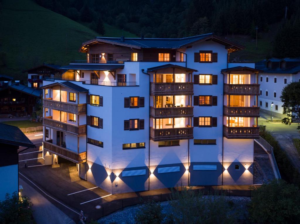 un grand bâtiment blanc avec de nombreuses fenêtres la nuit dans l'établissement The Peak Hochkönig, à Dienten am Hochkönig