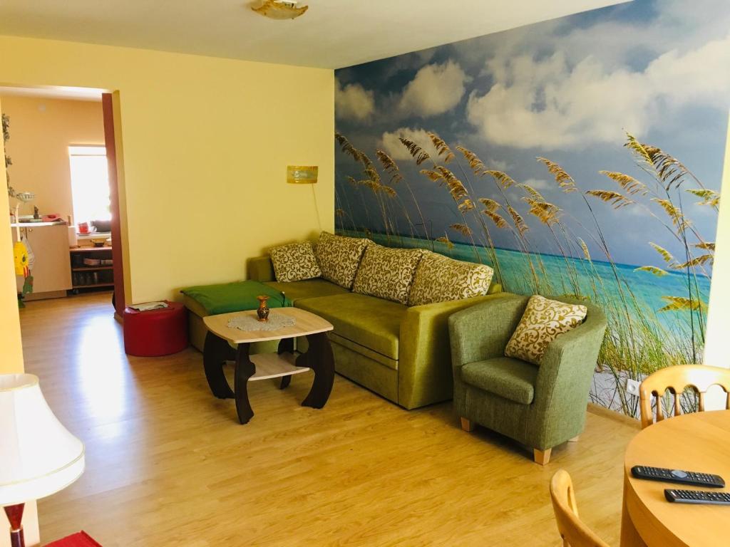 una sala de estar con un sofá verde y una pintura en River Apartments, en Šilutė