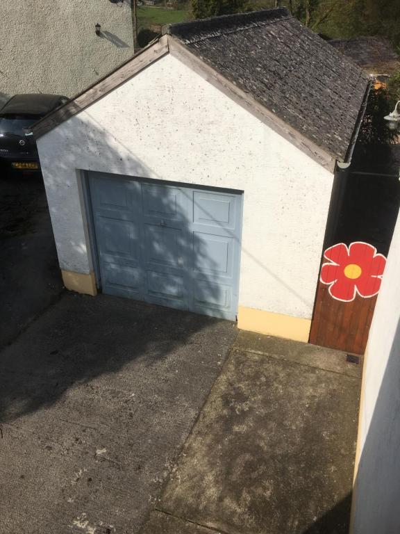 a garage with a blue garage door with a flower on it at Heddfan in Carmarthen