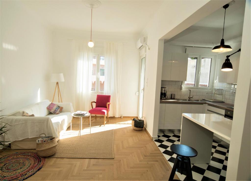 a living room with a white couch and a kitchen at My Megaro Flat in Athens