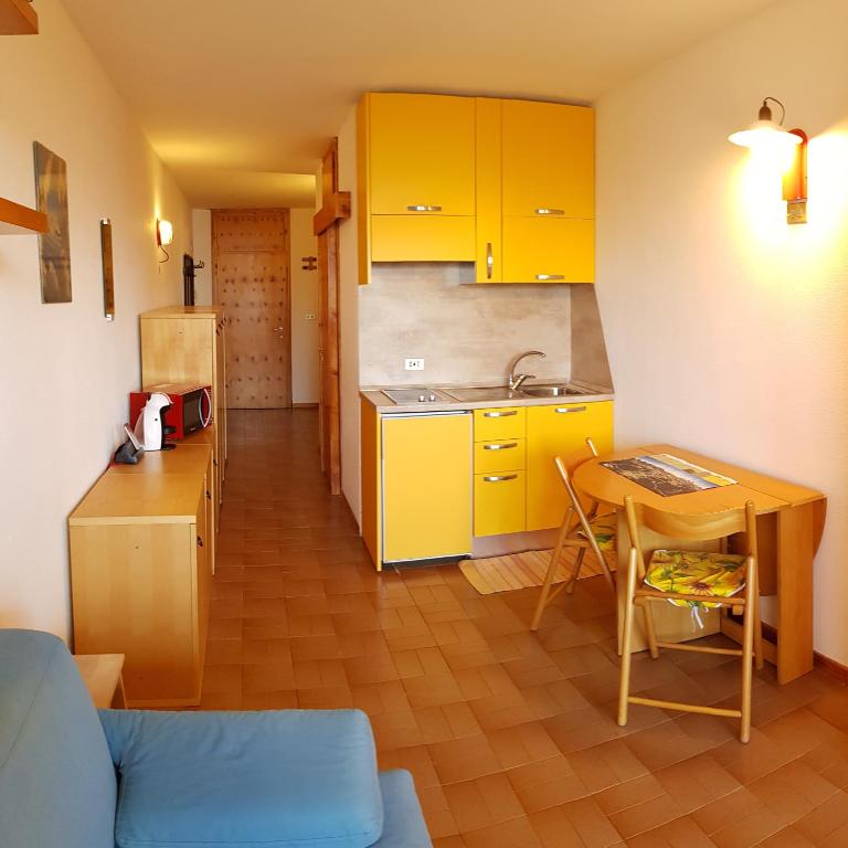 a kitchen with yellow cabinets and a table with a blue couch at La casa di Pila in Pila