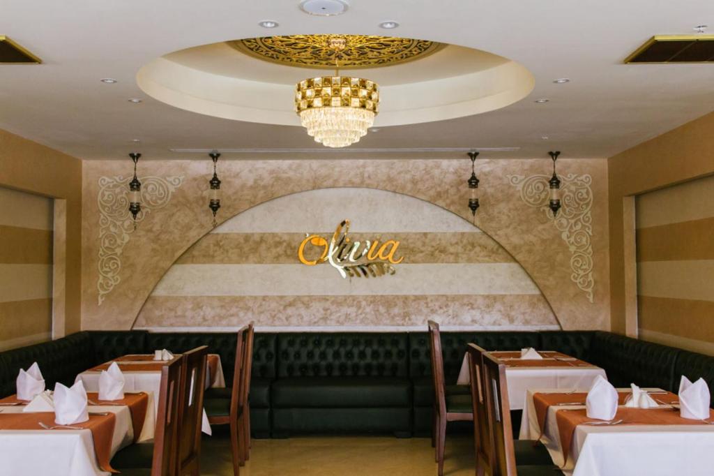 a dining room with tables and a chandelier at Mangrove Hotel in Ras al Khaimah