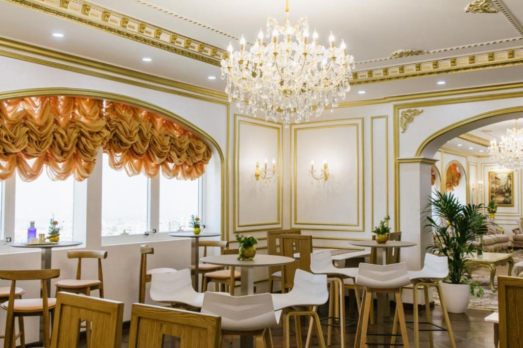 a restaurant with tables and chairs and a chandelier at Mangrove Hotel in Ras al Khaimah