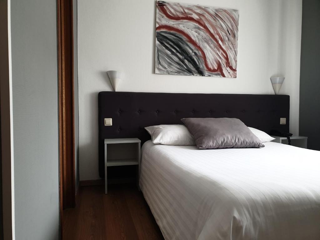 盧森堡的住宿－亞夏酒店，卧室配有一张床,墙上挂有绘画作品