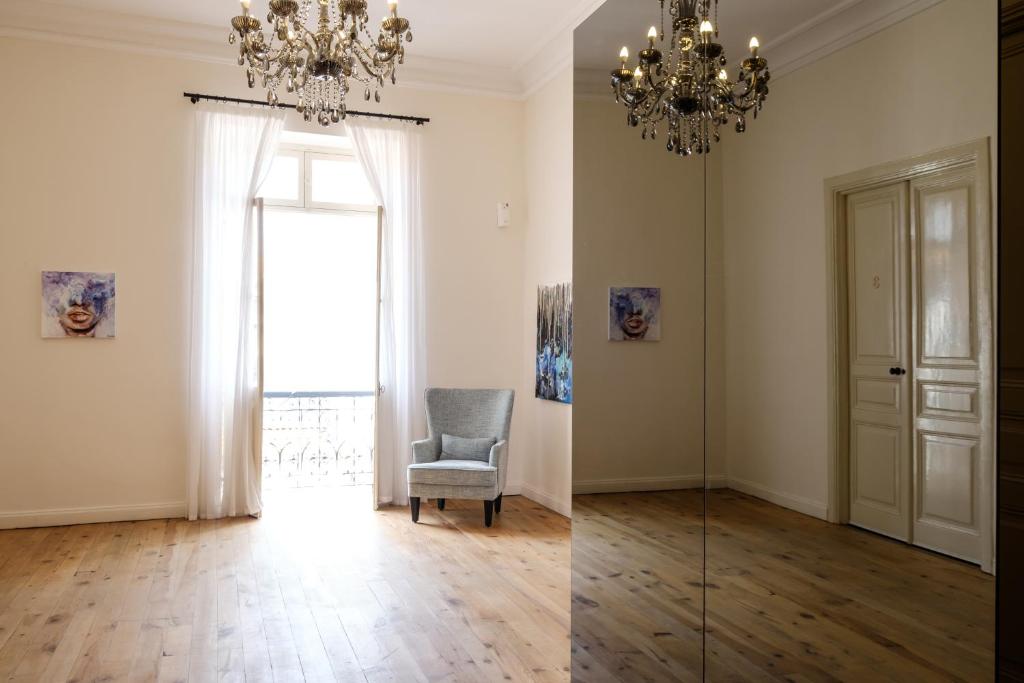 a living room with a chair and a chandelier at Limassol Old Town Mansion - Steps to the Sea , Marina and Center in Limassol