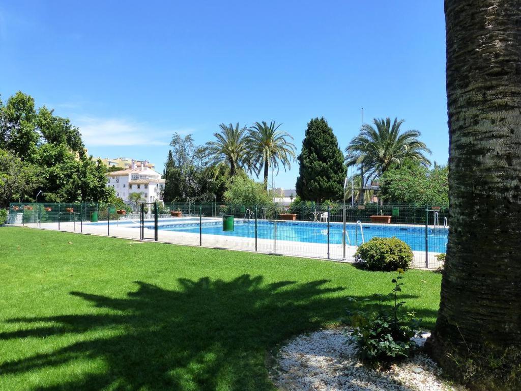 a large swimming pool in a park with a tree at Mar del Sur Apartamentos- Piscina y Playa - PARKING GRATIS in Benalmádena