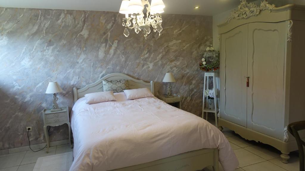 een slaapkamer met een bed en een kroonluchter bij Le jardin des secrets in La Voivre