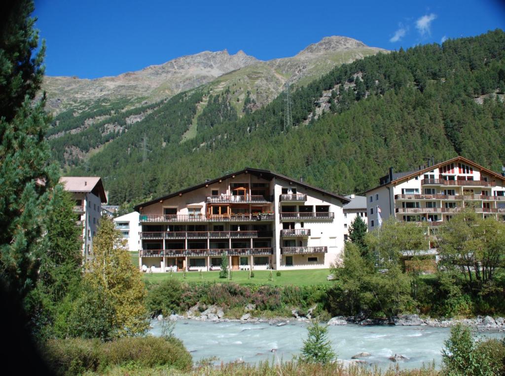 un bâtiment avec une rivière en face d'une montagne dans l'établissement Chesa La Furia, à Pontresina