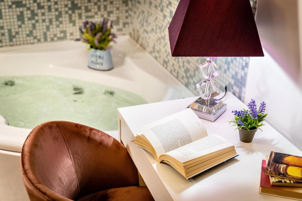 a desk with a book and a lamp on a table with a bath tub at Fior Di Loto Rooms in Cagliari