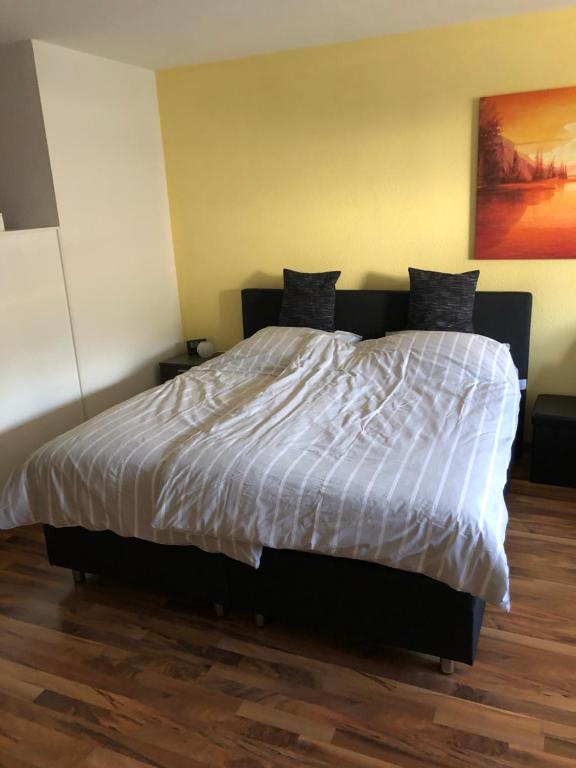 1 dormitorio con 1 cama con edredón blanco en kleine Ferienwohnung en Inzlingen