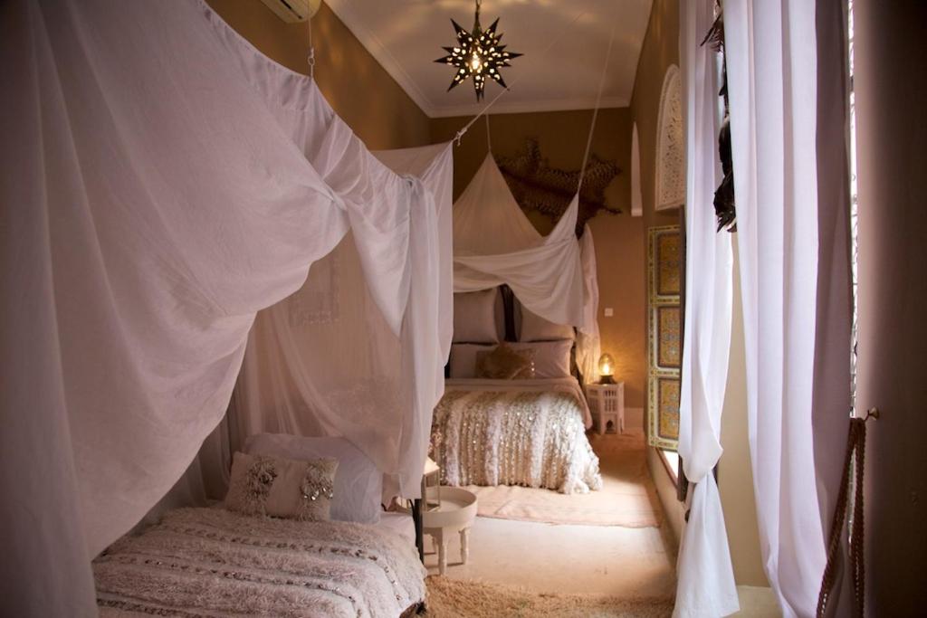 a bedroom with two beds with white drapes at The Bohemian Jungle in Marrakech