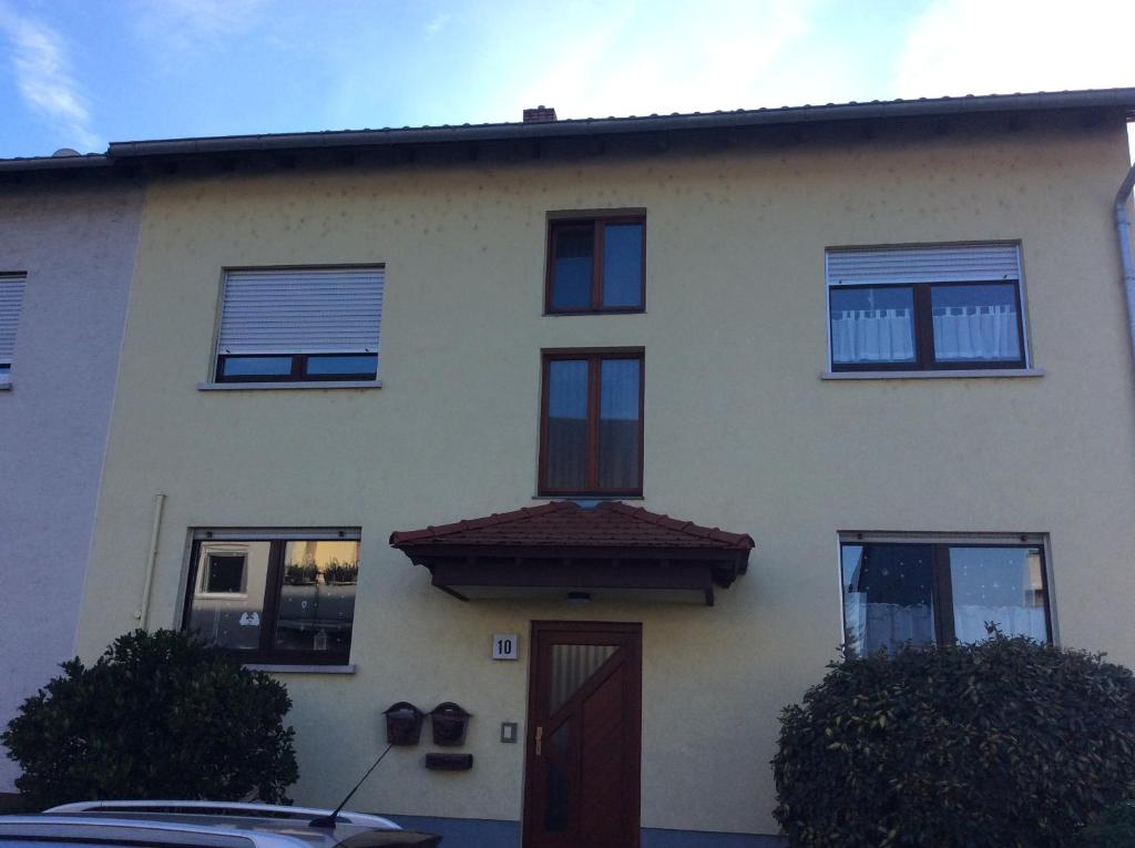 Casa blanca con puerta y ventanas marrones en Ferienwohnung Heddesheim, en Heddesheim