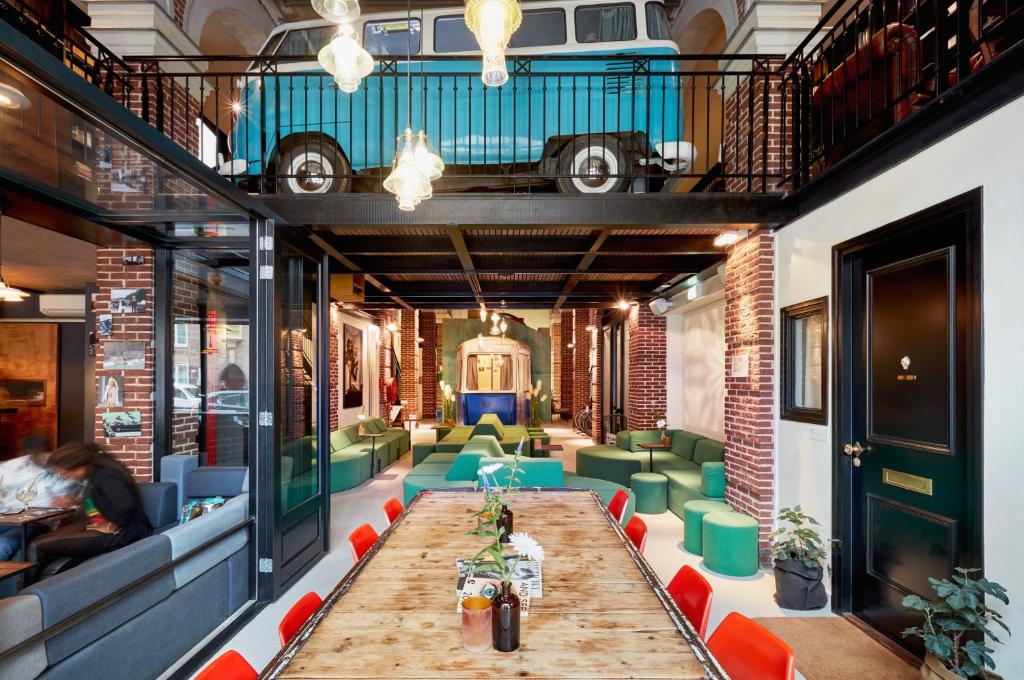 アムステルダムにあるHotel Not Hotel Amsterdamの長いテーブルと緑の椅子が備わる客室です。