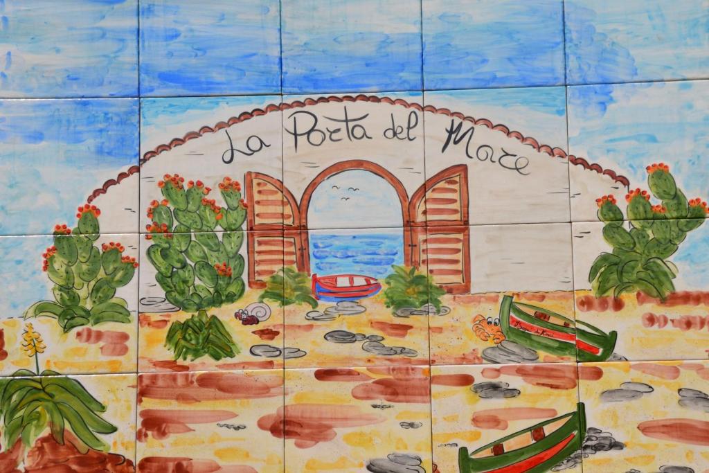a tiled wall with a picture of a beach and an ocean at La Porta del mare in Villapiana