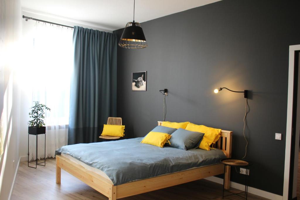 1 dormitorio con 1 cama con sábanas azules y almohadas amarillas en Simple & Elegant Apartment en Liepāja