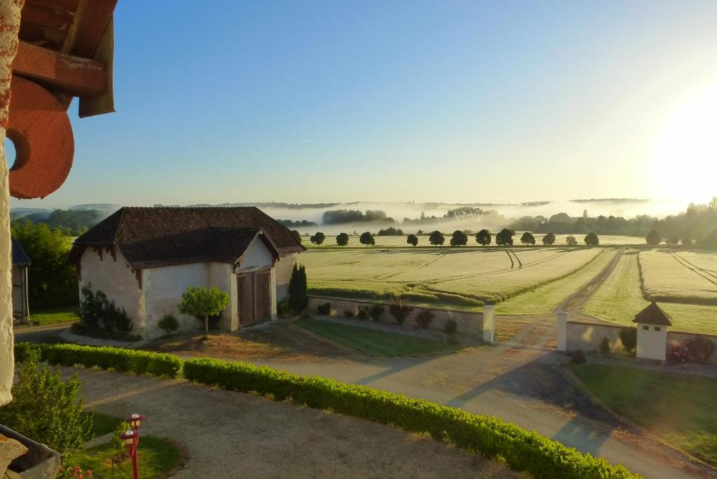 una vista de un campo con un edificio en el primer plano en Domaine de la Maison Neuve, en Saint-Jean-Saint-Germain