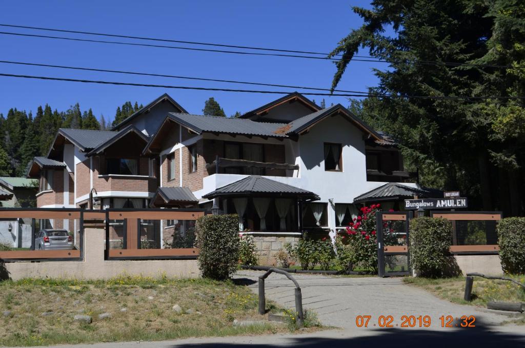 una gran casa blanca con techo negro en Apart Bungalows Amulen, en San Carlos de Bariloche