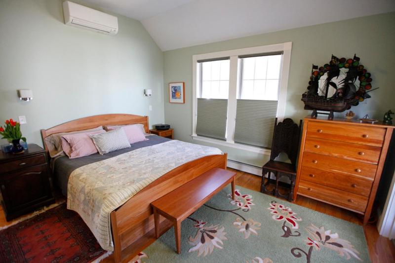 a bedroom with a bed and a dresser and windows at A Village Bed and Breakfast in Newton
