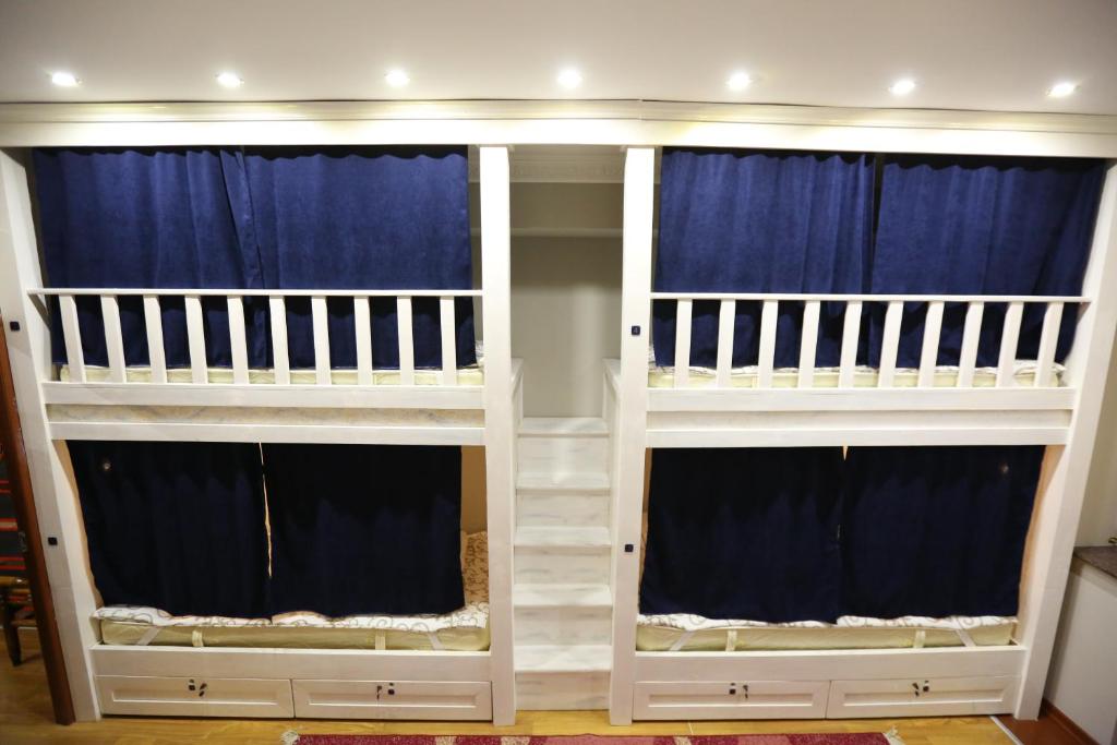 two bunk beds in a room with blue curtains at Avenue Hostel Yerevan in Yerevan