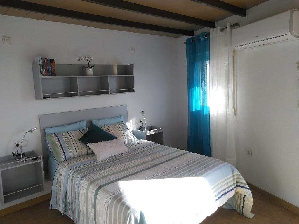 Apartamento El Almendrero في El Pueblo: غرفة نوم بسرير كبير مع ستائر زرقاء
