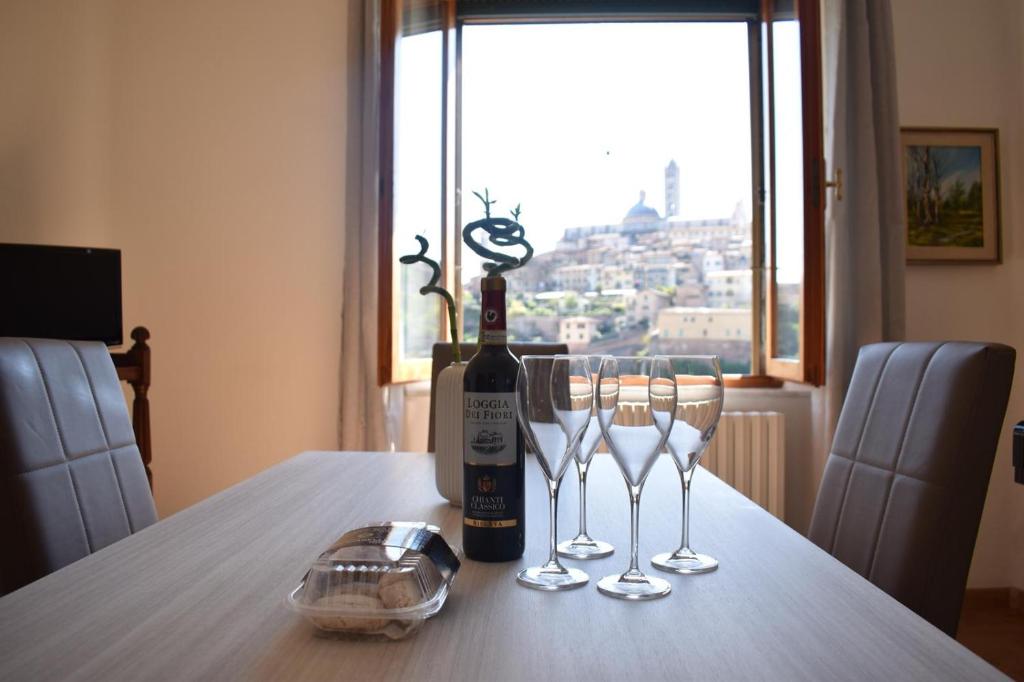 una bottiglia di vino seduta su un tavolo con bicchieri di La Finestra su Siena a Siena