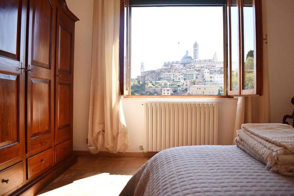 sypialnia z łóżkiem i dużym oknem w obiekcie La Finestra su Siena w Sienie