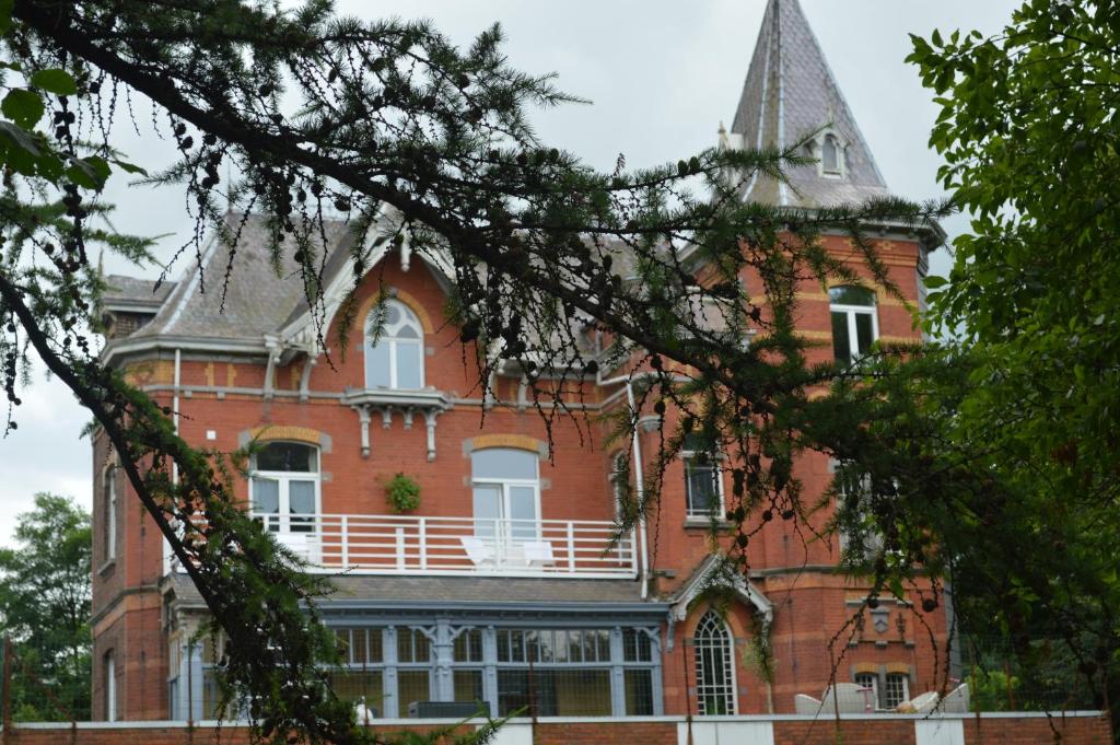 un gran edificio de ladrillo rojo con una torre en B&B Chatelet Cremers en Verviers