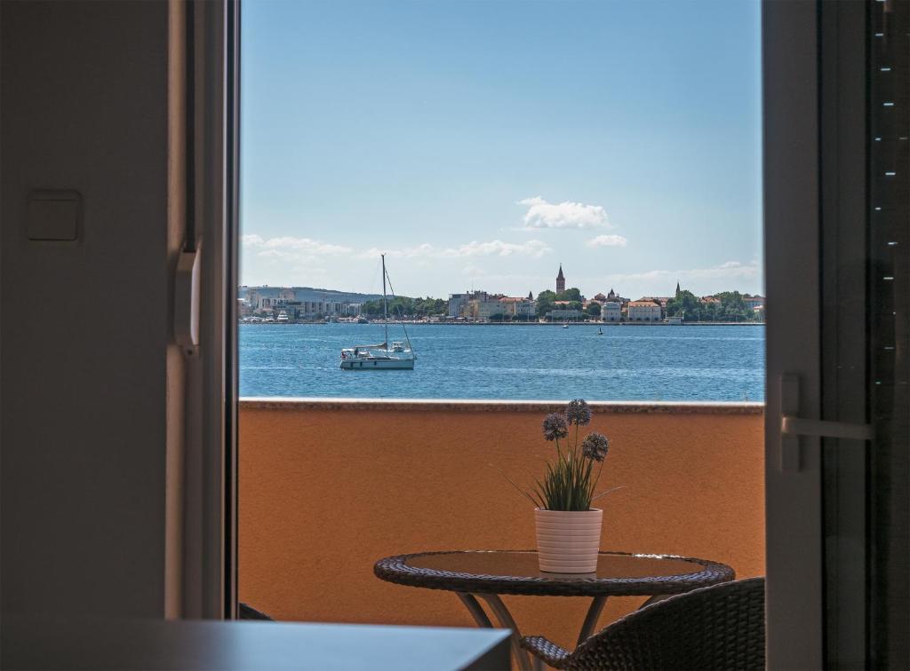 a balcony with a table and a boat in the water at Apartments Nino 1 in Zadar