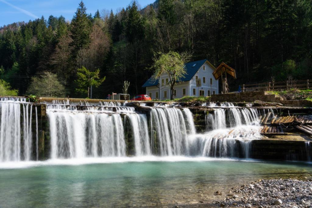 a waterfall in front of a house next to a house at Boutique rooms Pri Rogovilcu in Solčava