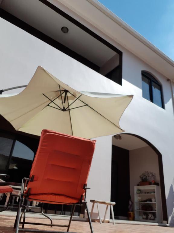 une chaise rouge et un parasol devant une maison dans l'établissement Casa Sur, à Tegucigalpa