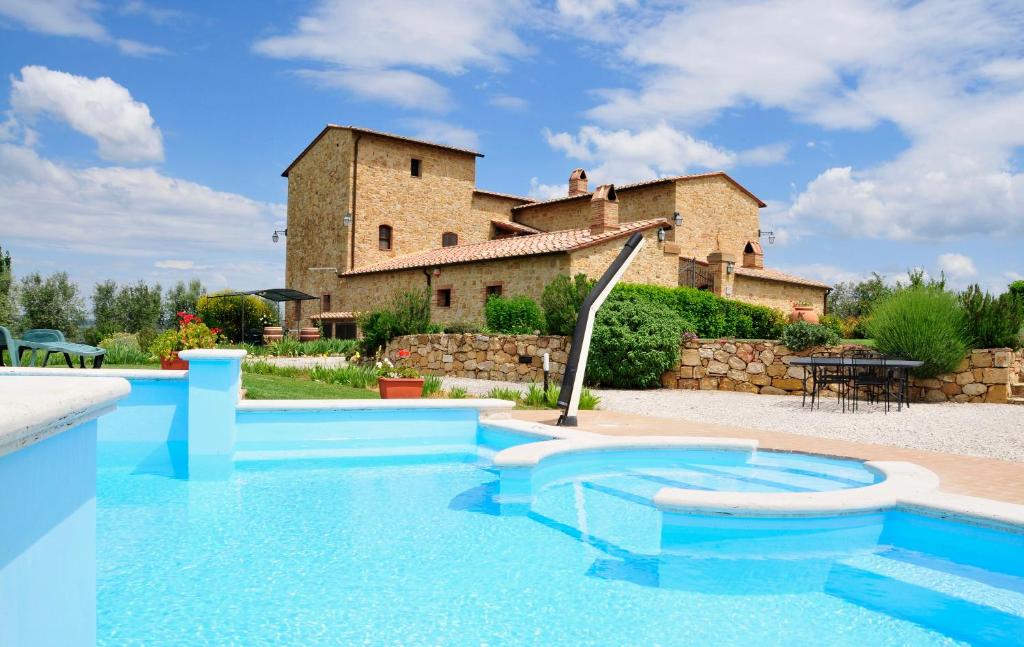 a house with a swimming pool in front of a building at Agriturismo Il Macchione in Pienza