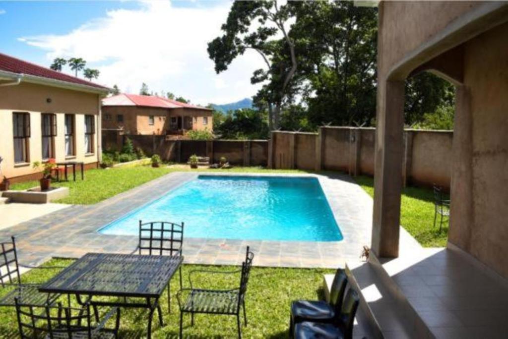 a swimming pool with chairs and a table in a yard at Wadonda Suites in Zomba