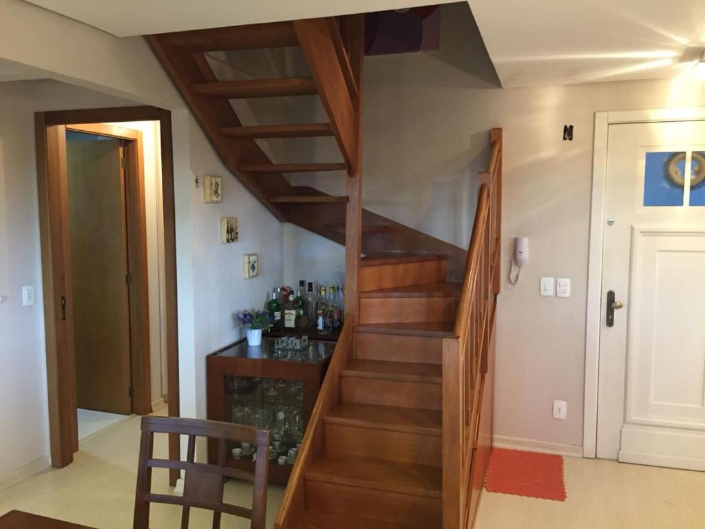 uma escada de madeira num quarto com uma porta em Centro Gramado-LOCALIZAÇÃO PERFEITA em Gramado