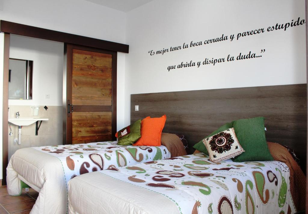 a bedroom with two beds and a sign on the wall at Hostal Almagro in Almagro