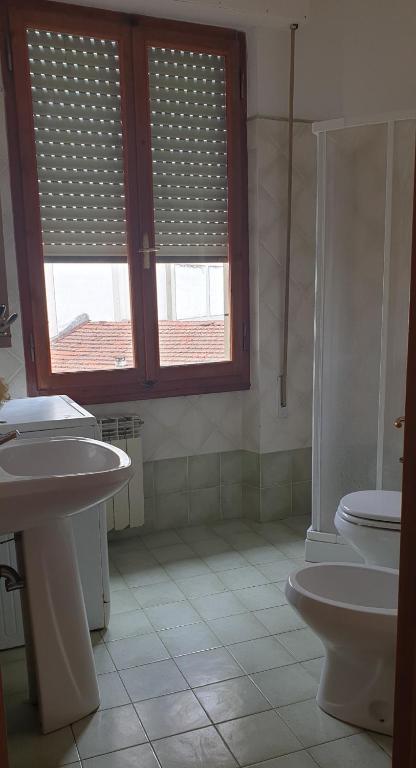 łazienka z 2 umywalkami, toaletą i oknem w obiekcie Ladybug Apartment w mieście Poggibonsi
