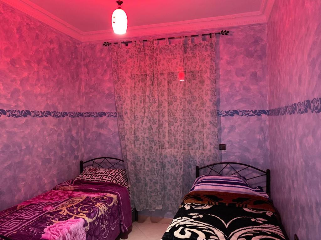 2 camas en una habitación con paredes rosas en Résidence Al Osra, en Agadir