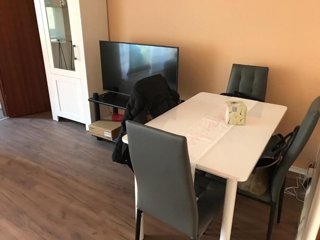 a room with a white table and chairs and a television at Central-Apartment-Adria in Saarbrücken