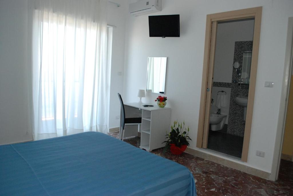 a bedroom with a bed and a desk with a mirror at Maniel Beach Hotel in Letojanni