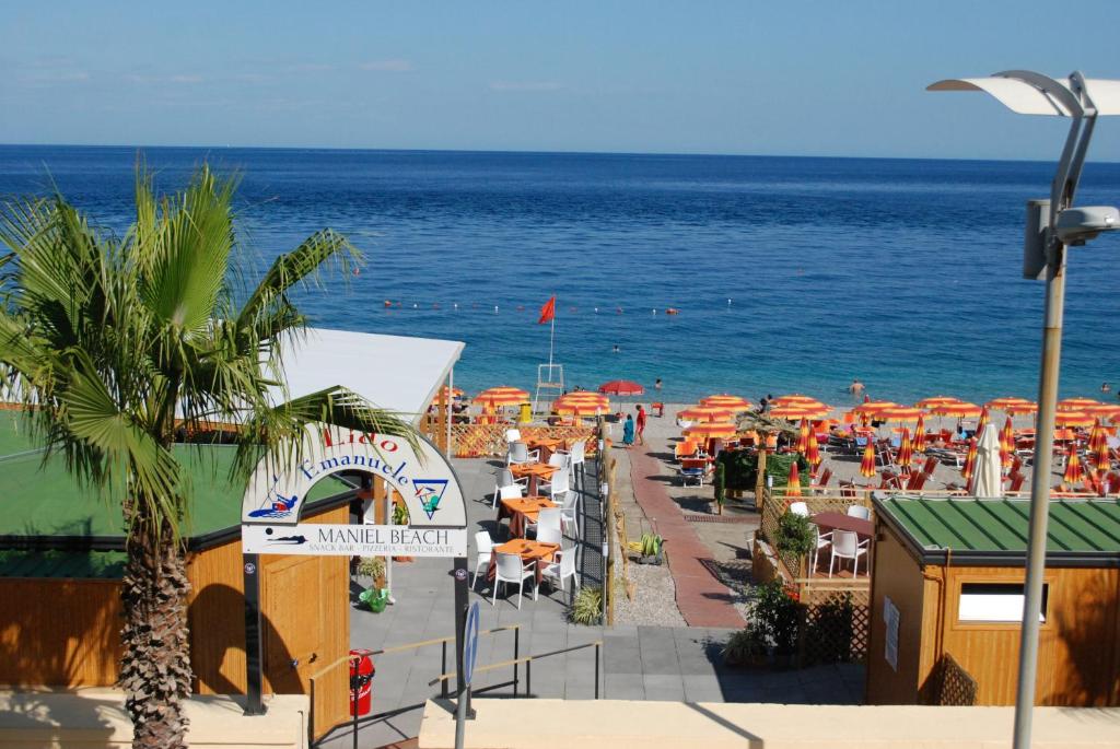 a beach with a bunch of umbrellas and the ocean at Maniel Beach Hotel in Letojanni