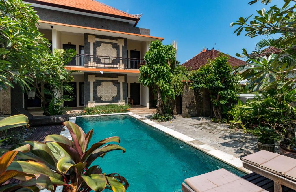 a swimming pool in front of a house at Eddys Cottages & Villa in Legian