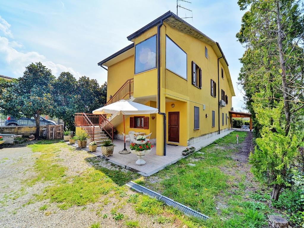 una casa gialla con un ombrello in un cortile di Villa Magnolia a Bolsena