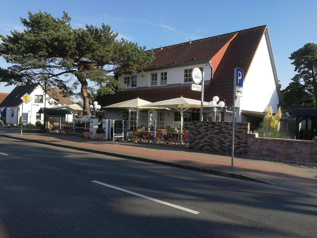 a building with tables and umbrellas on the side of a street at Appartements Fischerhus in Glowe