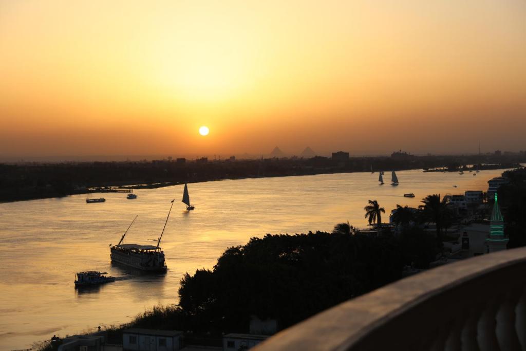 una puesta de sol sobre un río con barcos dentro en Maadi, Direct Nile river View From all Rooms en El Cairo