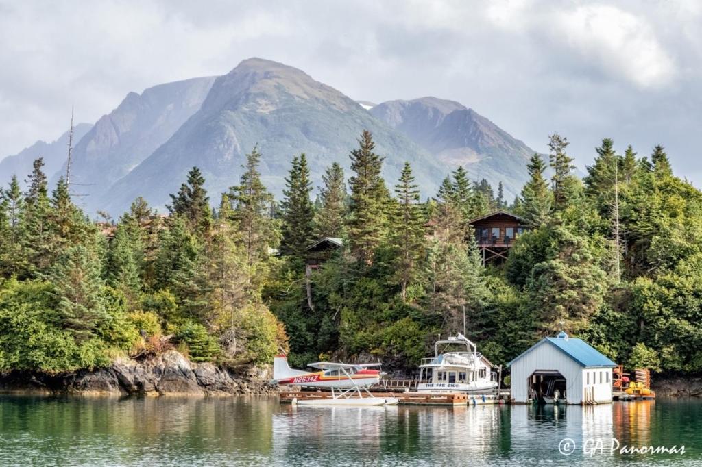 a lake with a house and a boat on the water at Stillpoint Lodge - All-Inclusive in Halibut Cove