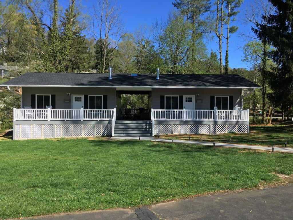 une maison avec une terrasse couverte et une pelouse dans l'établissement Brookside Cottages, à Waynesville