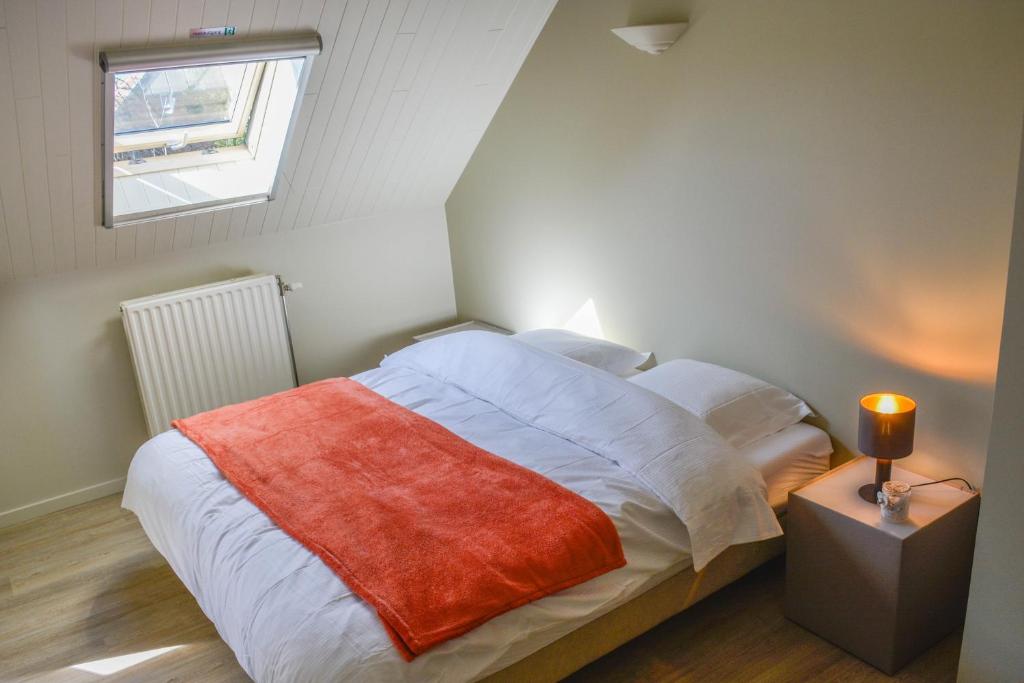 a bedroom with a bed with a red blanket and a window at B&amp;B Onderweg in Horebeke