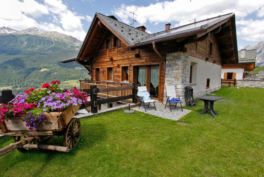 eine Blockhütte mit Blumen in einem Wagen davor in der Unterkunft Chalet Teo e Marianna in Bormio