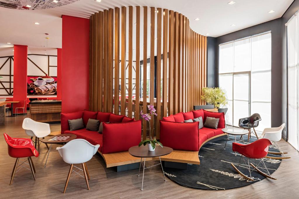 布盧梅瑙的住宿－ibis Blumenau，客厅配有红色沙发和白色椅子