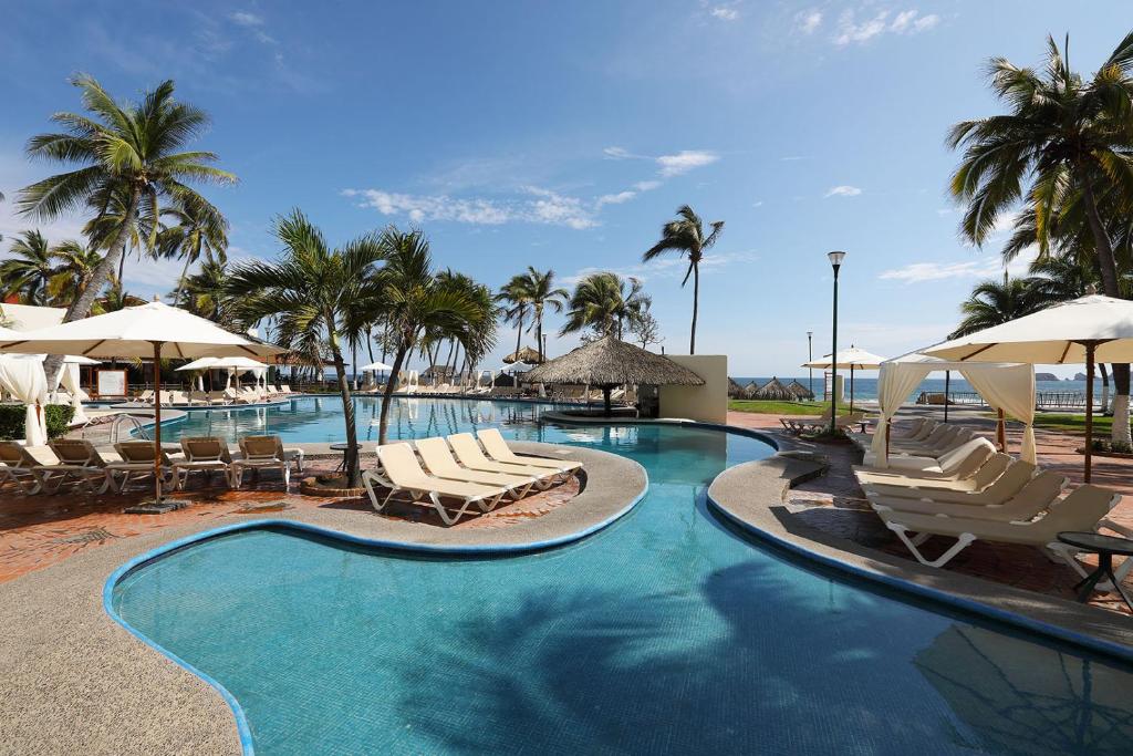 伊斯塔帕Emporio Ixtapa - with Optional All Inclusive的一个带椅子和遮阳伞的游泳池以及棕榈树